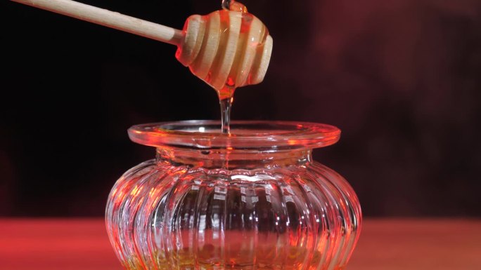 液体新鲜蜂蜜。金蜜滴，从木勺里倒出来。健康有机蜂蜜滴。