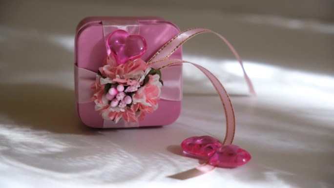粉色礼盒里有鲜花，水晶心，阳光。婚礼，生日，情人节。模板贺卡。快乐的庆祝活动