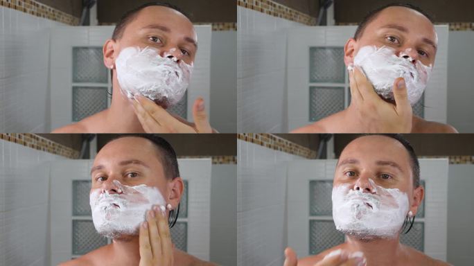 英俊的成年男子在脸上涂抹剃须泡沫