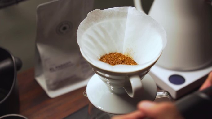 咖啡师将刚磨碎的咖啡倒入带有纸质过滤器的陶瓷滴管中