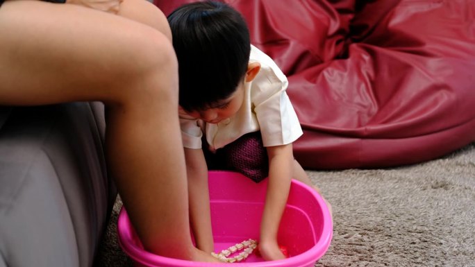 亚洲男孩在母亲节给妈妈洗脚以示爱。