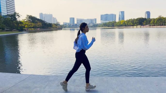 亚洲女运动员在湖边的城市跑步