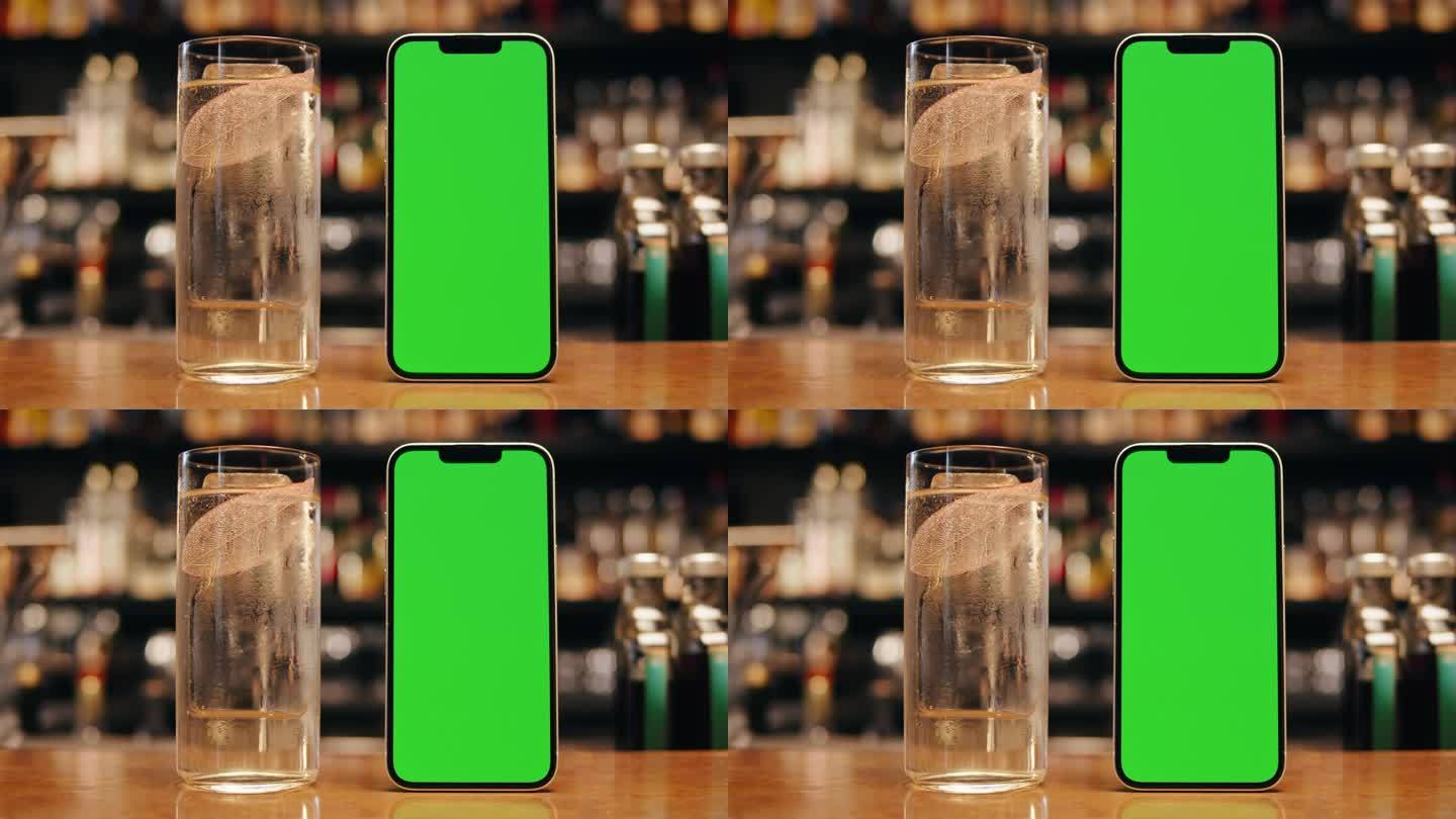 桌上有绿色屏幕的智能手机。色度键电话在酒吧和一些饮料站在吧台上。送货菜单咖啡厅酒吧餐厅
