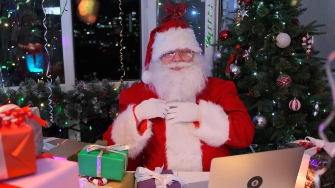 圣诞老人捋着胡子祈求好运，哈哈大笑，坐在他的住所里，堆着新年礼物