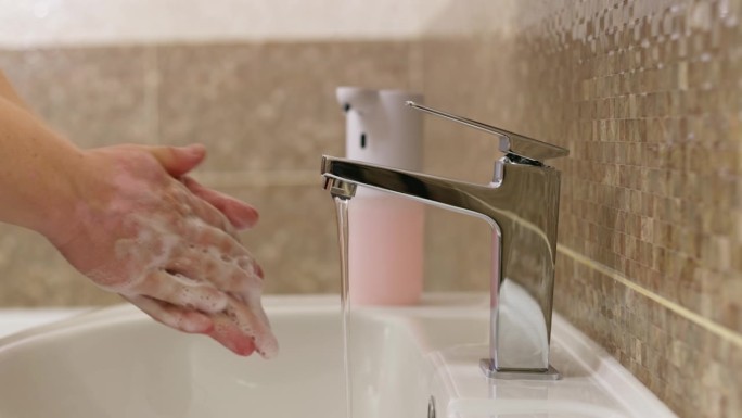 男人在浴室里用泡沫肥皂洗手。日常卫生习惯。健康的习惯