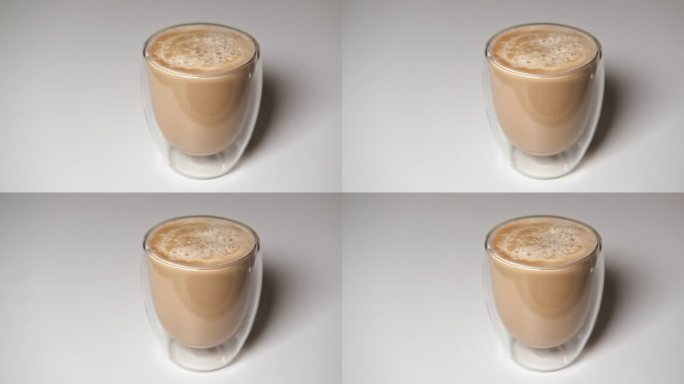 近距离倒牛奶到透明双层玻璃杯黑咖啡。在透明卡布奇诺杯中加入奶精。准备新鲜拿铁。牛奶与早咖啡的混合。酝
