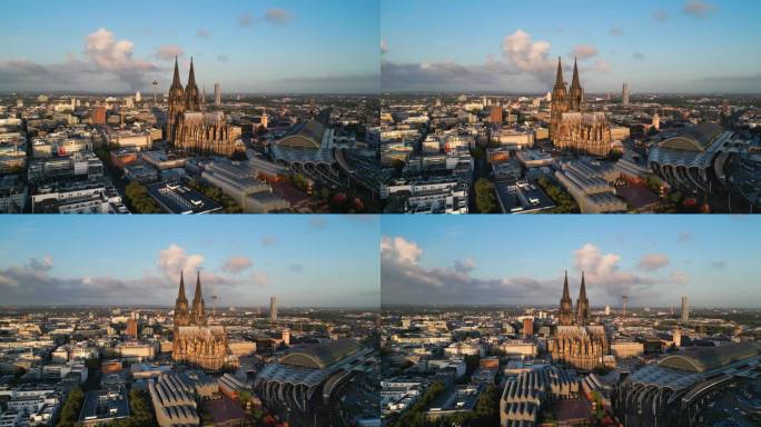 鸟瞰图实时镜头飞行通过科隆大教堂，科隆中央车站，音乐圆顶和霍亨索伦桥与火车运行在日出时间在科隆市中心