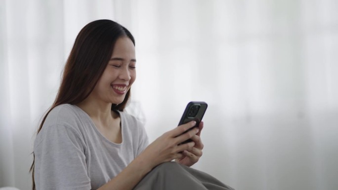 一个亚洲女人在床上看手机