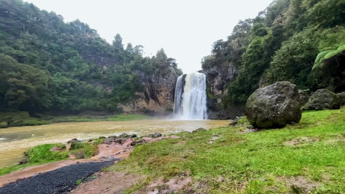 虎花瀑布在雨天汇入浑浊的河水，广角慢镜头