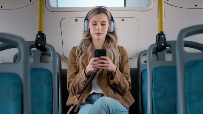 耳机、手机和年轻女子早上在公交车上听音乐、播放列表或专辑。来自加拿大的快乐、微笑和女性在乘坐公共交通
