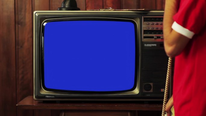 一个人一边看旧电视一边用旧电话，蓝屏，4K分辨率。