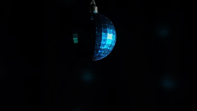 装饰镜球与蓝色反射旋转在黑色背景与复制空间。旋转新年玻璃球。