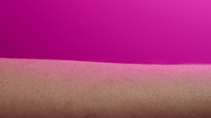 手部皮肤在粉色霓虹灯下，人体部位和紫外线，手臂表面微距拍摄。