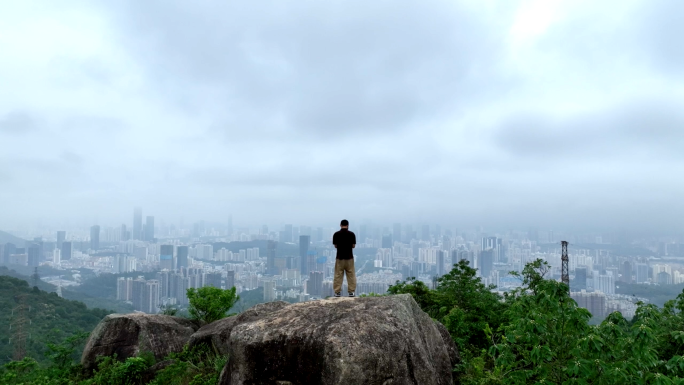 山顶石头上一个人俯瞰整个城市