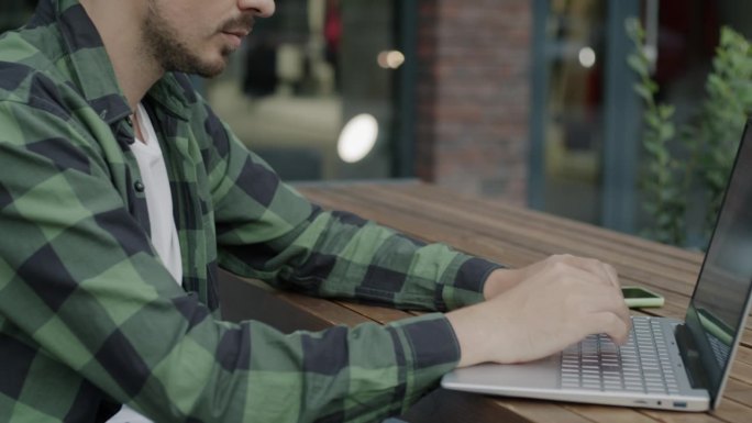 中东企业家在户外露天咖啡馆用笔记本电脑打字，忙于远方的工作
