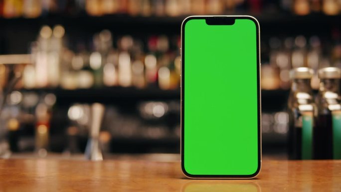 桌上有绿色屏幕的智能手机。色度键电话在酒吧和一些饮料站在吧台上。送货菜单咖啡厅酒吧餐厅