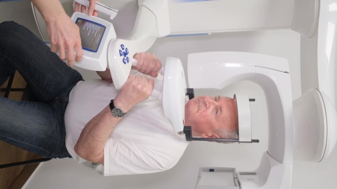 一个老人在x光机上的垂直视频，有一个头颅测量孔。