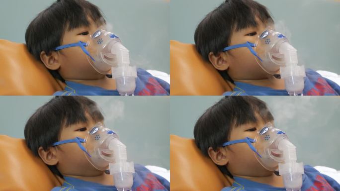 一名患有哮喘的亚洲男孩在医院接受喷雾器治疗。