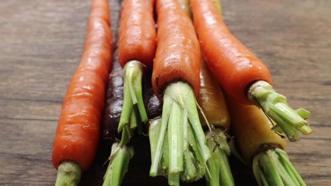五颜六色的小胡萝卜，木质背景上营养健康的食物。