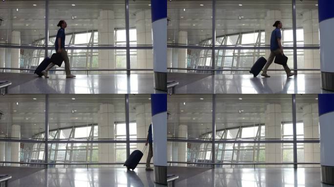 在现代化的机场航站楼，一名男子带着带轮子的行李箱和手提电脑包走过