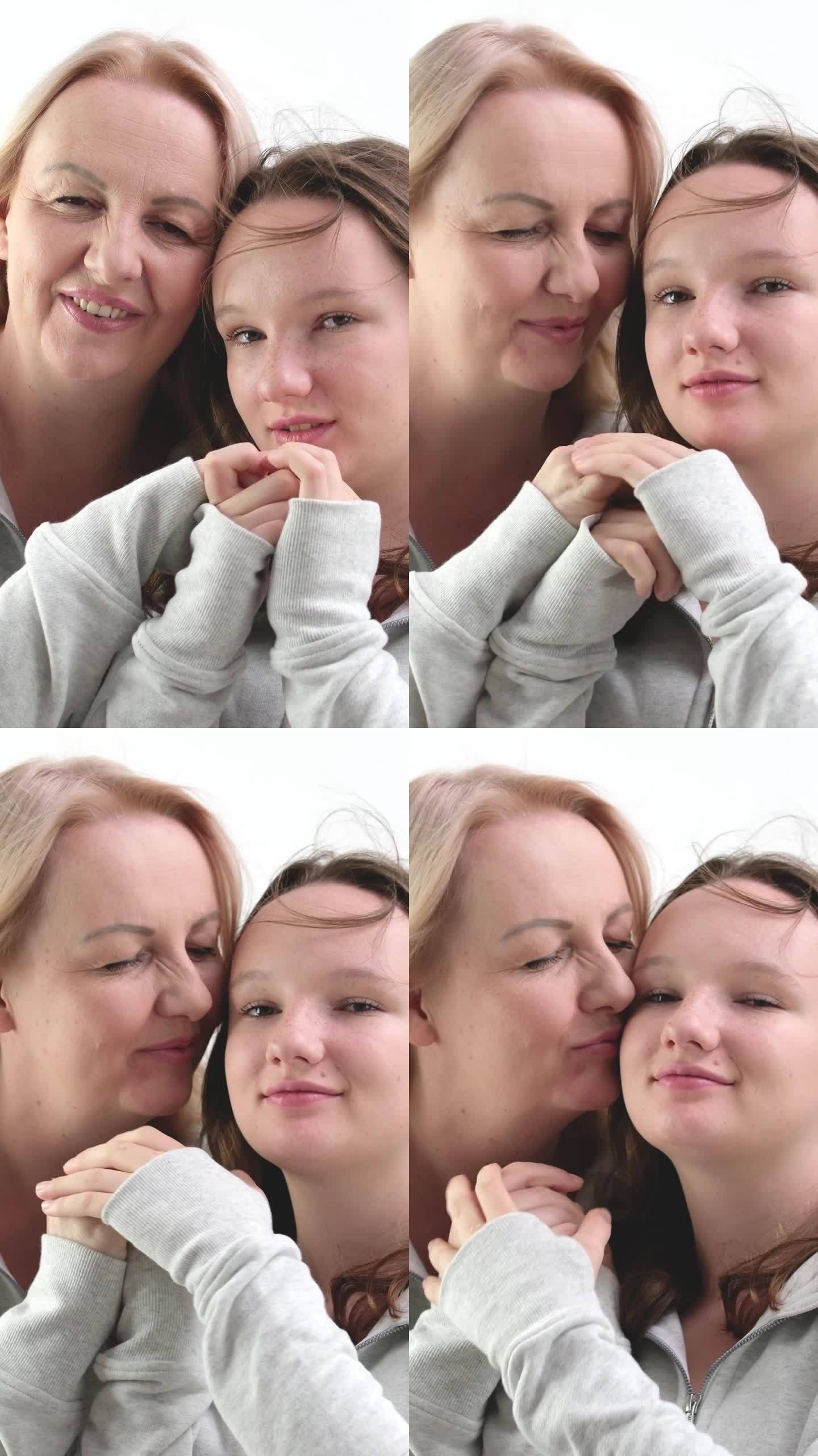 爱的女儿和母亲拥抱亲吻温柔女孩吻母亲的手母亲拥抱亲吻女儿的脸颊两个女人在浅色的背景很多温柔和喜悦的爱
