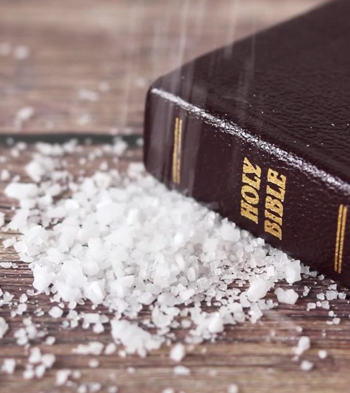 海盐洒在木桌上，还有合上的圣经，特写