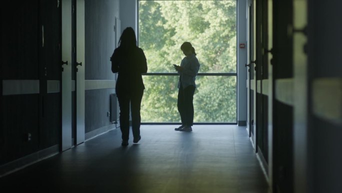 医护人员和病人走在昏暗的诊所走廊里