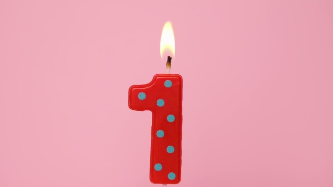 一周年纪念视频横幅燃烧斑点红色和绿色一号蜡烛在浅粉红色的背景。4K分辨率生日快乐横幅