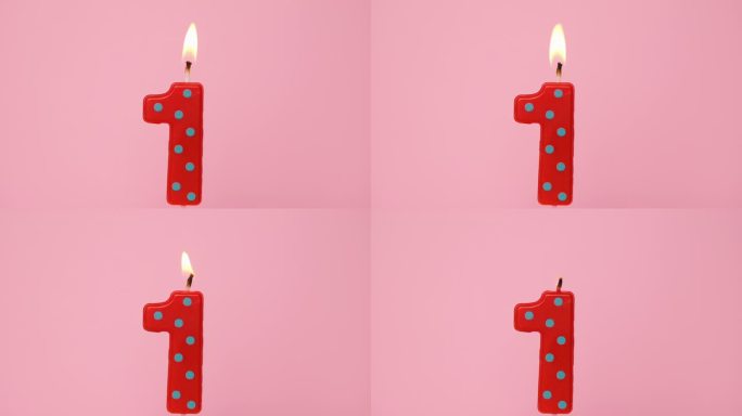 一周年纪念视频横幅燃烧斑点红色和绿色一号蜡烛在浅粉红色的背景。4K分辨率生日快乐横幅