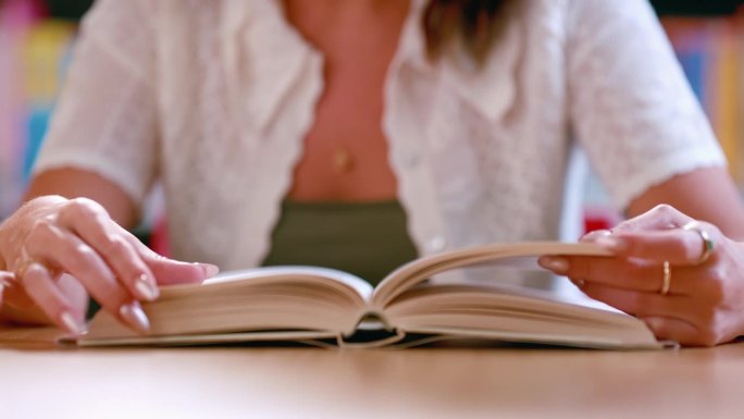 妇女，双手和阅读书籍在图书馆为文学，知识或教育和研究。女性或学生在书店翻页学习、学习或获取信息的特写