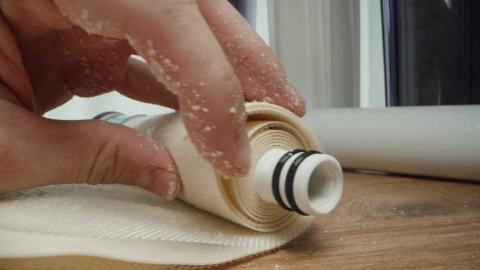 一个切开的水膜过滤器的脏层，手上覆盖着硬水的白色水垢。特写镜头。家用滤水器更换概念。