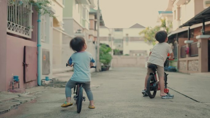 精力充沛的亚洲兄弟在城市骑小自行车:积极的家庭乐趣和学习。