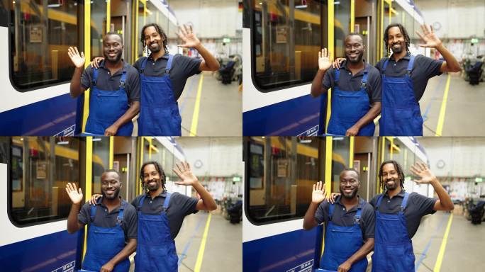 两位年轻的火车工程师在铁路维修车间一起挥手的肖像