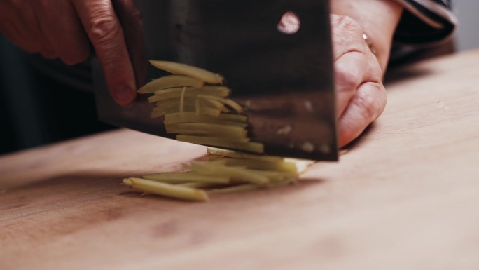 用刀在橄榄木板上切鲜姜