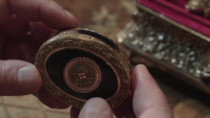 古玩家检查过的装有宝石的铜首饰盒