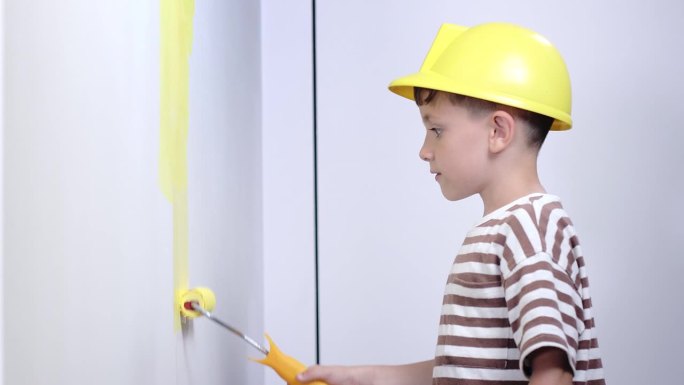 家庭装修时，男孩在墙上刷黄漆。