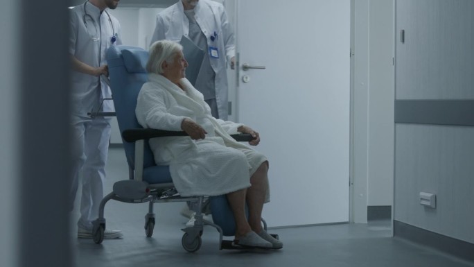 在诊所走廊里，医生与女病人一起推着轮椅