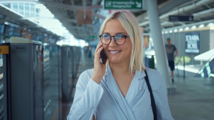 一个女人在地铁里打电话。特写:积极乐观的女商人在大城市里讲智能手机。微笑的女商人在打电话。肖像，友善