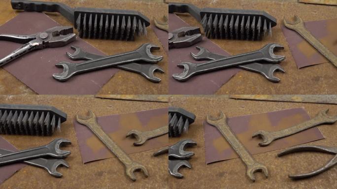 生锈的金属片上躺着工作和生锈的旧仪器、砂纸和钢丝刷。清理和修复旧仪器