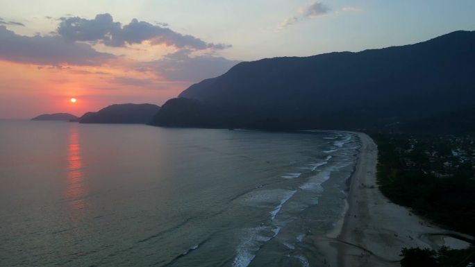 航拍无人机缓缓降落在沙滩上，远处夕阳渐暗