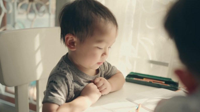 创意家庭教育:两个亚洲兄弟男孩在纸上享受彩色铅笔绘画。