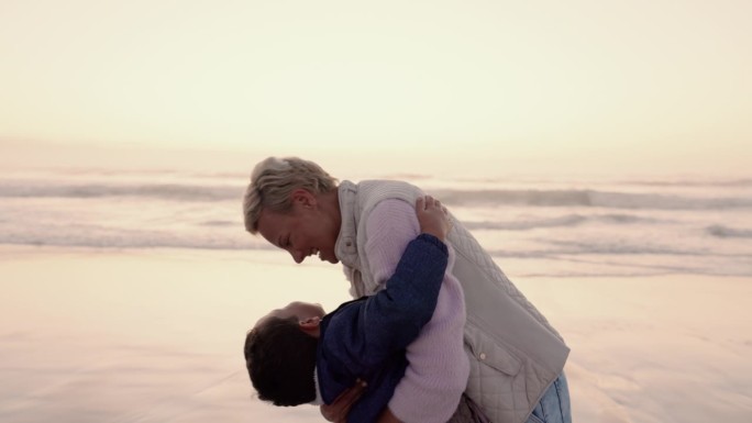 妈妈和男孩在沙滩上拥抱，夕阳和疯狂的笑声充满爱，在假期的海浪中关怀和联系。妈妈、男孩和妈妈一起玩着有