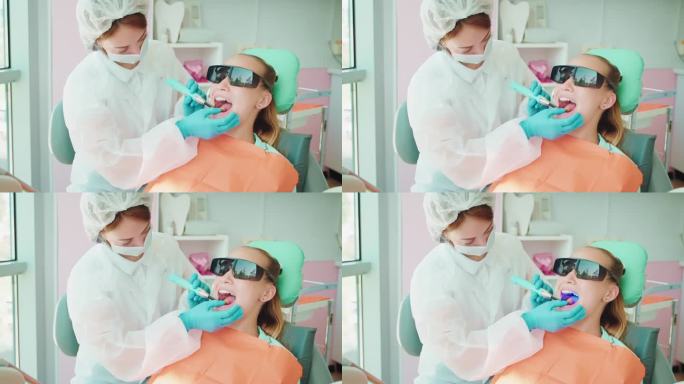 牙医在少女的牙齿上安装牙齿填充物，发出蓝光，治疗龋齿
