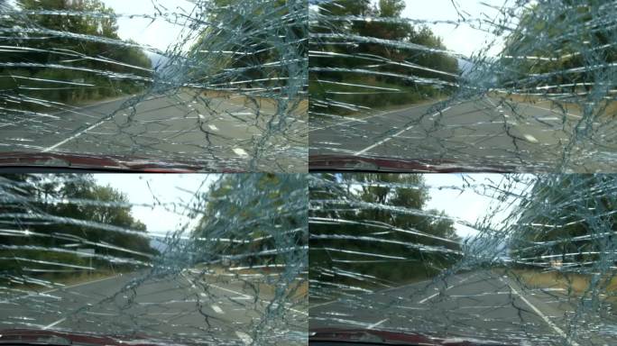从一辆行驶在挡风玻璃破裂的道路上的汽车里看到的景象。4 k的视频。