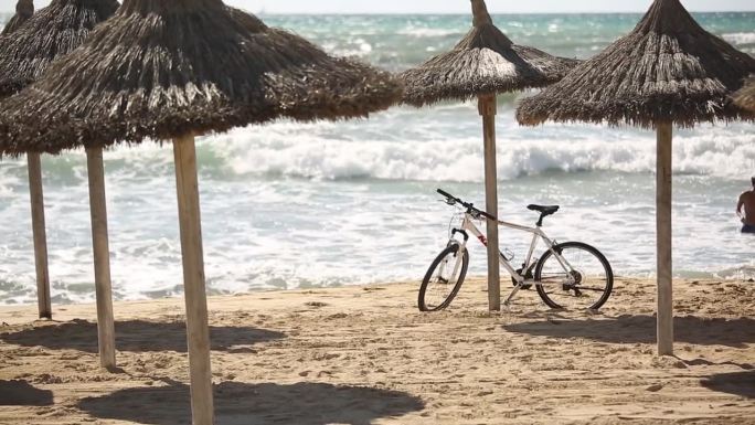 自行车倚在沙滩上的天篷上，眺望着大海的大浪