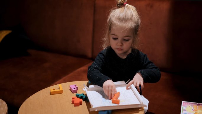 3岁的小女孩在室内玩木制的俄罗斯方块
