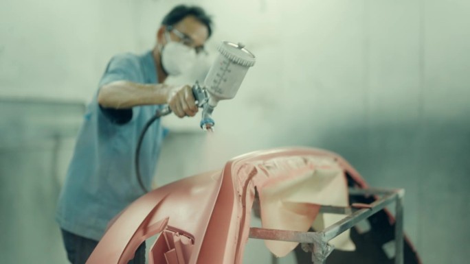 工艺在行动:亚洲技术员提高汽车与细致的喷枪喷漆。