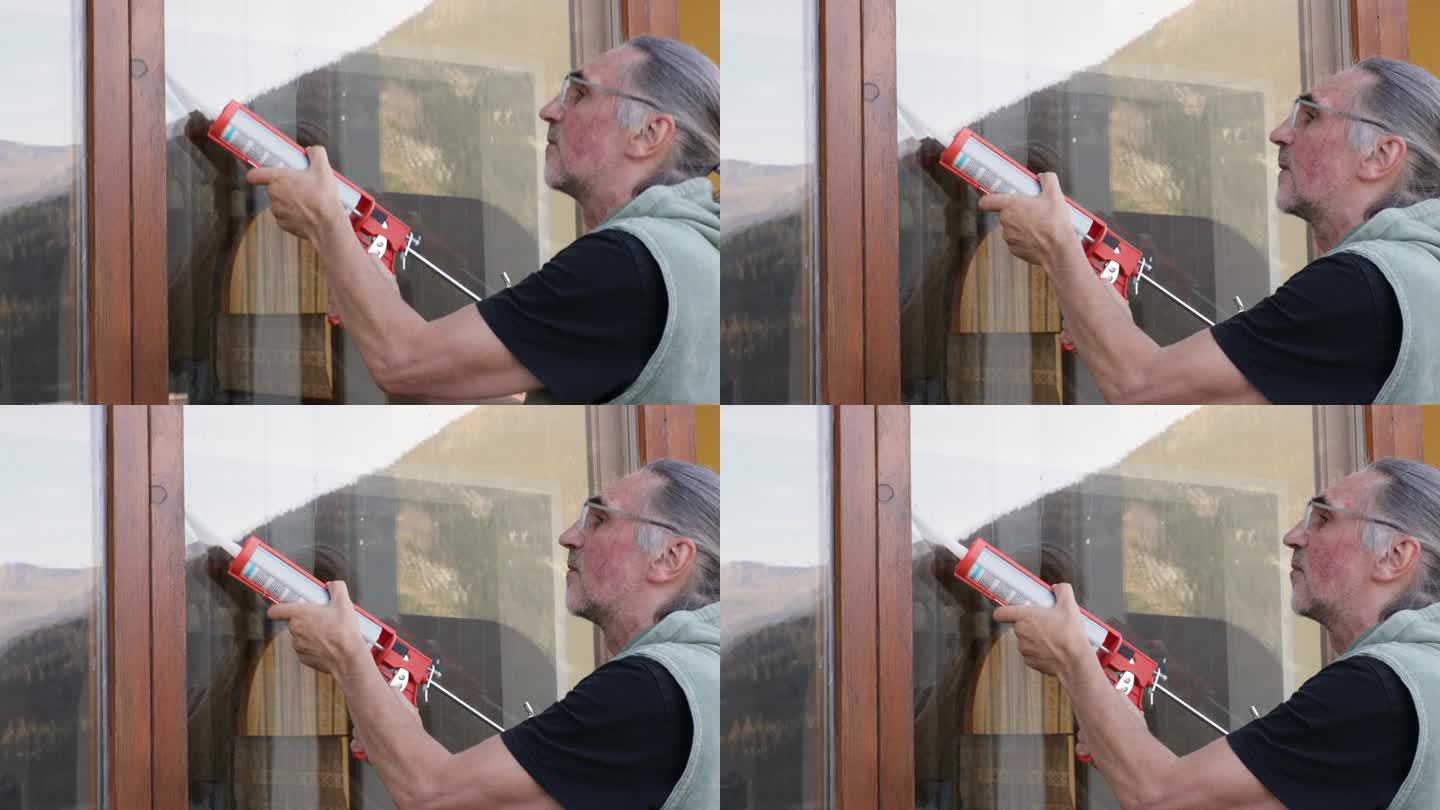 白发苍苍的房子主人用硅胶来处理全景窗的门缝，反射出山景。