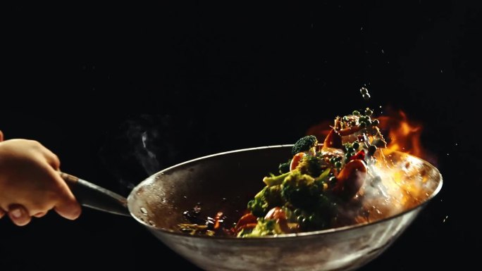 厨师烹饪美味的炒面，炒菜和虾在黑色背景的火焰锅