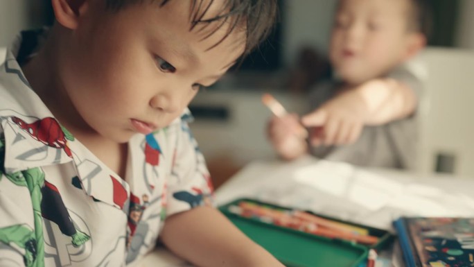 儿童教育与艺术表现:亚洲男孩通过彩色铅笔画享受家庭作业。